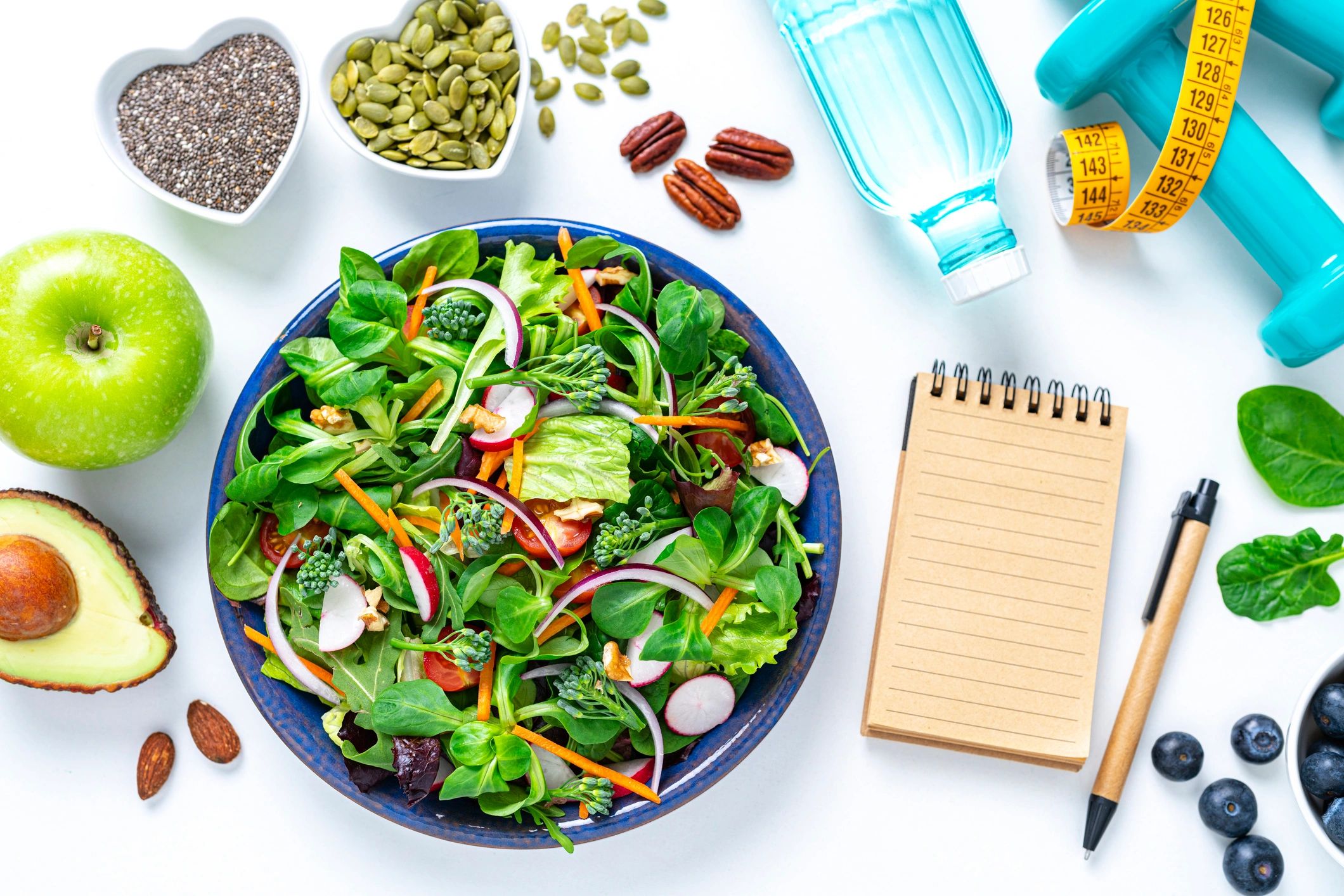 Healthy meal planning materials with salad and notebook